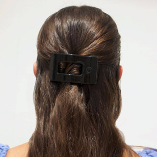 Back view of a woman's hair styled in a half-up look secured with a flat rectangle hair clip.