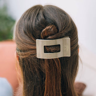 Woman wearing sage green rectangular hair clip in brown hair styled in half-up twist