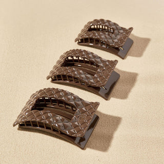 Three brown quilted rectangular hair clips with curved design displayed on neutral background