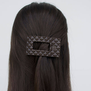 Woman wearing a quilted rectangular hair clip in dark taupe holding back brunette hair.