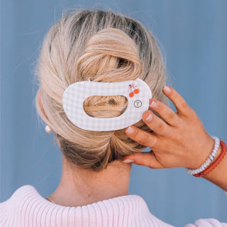 Woman wearing white oval hair clip with cherry design in blonde updo hairstyle