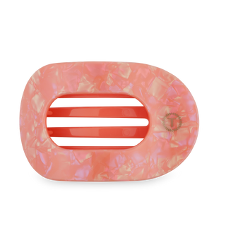 Large flat round hair clip in translucent coral-pink tone with geometric pattern design