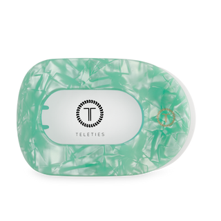 Translucent green hair clip with oval opening and textured surface, branded with TELETIES logo