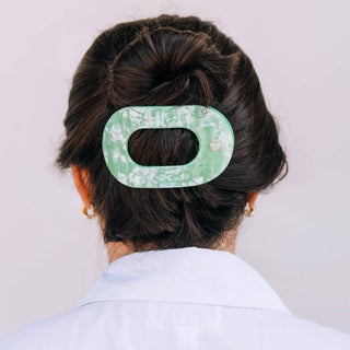 Woman wearing large flat round hair clip in updo hairstyle, viewed from behind