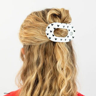 Woman wearing white Mickey Mouse patterned hair clip securing a messy bun hairstyle from behind.