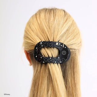 Black oval hair clip with Disney Mickey Mouse pattern holding blonde hair in half-up style.