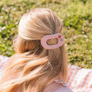 Woman wearing pink gingham flat round hair clip in blonde hair outdoors