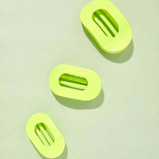 Three bright green oval-shaped flat hair clips with ridged grips displayed on light background