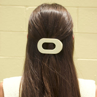 Woman wearing a flat round hair clip with oval opening in long brown hair