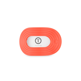 Orange flat round hair clip with ribbed texture and white TELETIES logo label