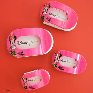 Four pink Minnie Mouse hair clips with Disney branding displayed on coral background