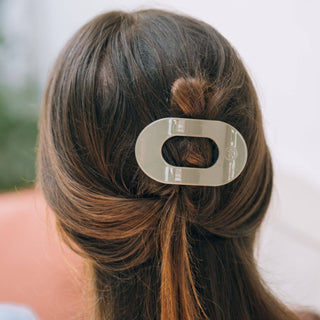Woman wearing sage green flat round hair clip securing half-up hairstyle from behind