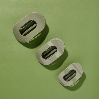 Three oval-shaped hair clips with translucent finish arranged on green textured surface with shadows