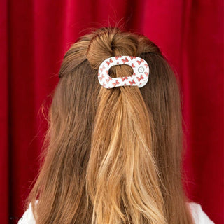 Woman wearing TELETIES flat round hair clip with Minnie Mouse bow pattern in half-up hairstyle.