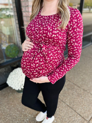 Pregnant woman wearing floral long sleeve maternity nursing top with tie waist and black leggings