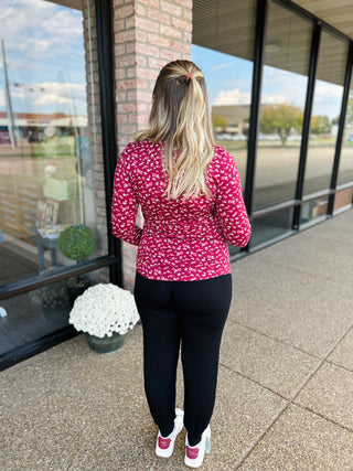 Woman wearing floral print long sleeve maternity nursing top with dark pants, viewed from behind.
