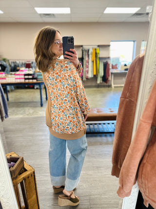 Woman in boutique mirror selfie wearing Haptics floral colorblock pullover top with wide-leg jeans.