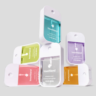 Six Touchland Power Mist Hydrating Hand Sanitizer spray bottles arranged in a stacked pyramid display.