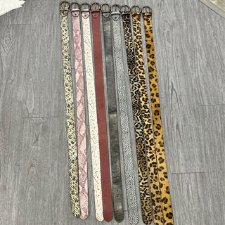 Nine genuine leather belts in various animal print and solid patterns displayed on gray wood floor