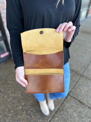 Person holding open handcrafted leather wallet showing interior compartments and yellow suede lining