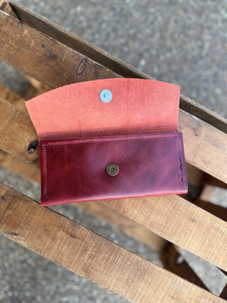 Handcrafted leather wallet with magnetic closure displayed open on wooden surface showing interior and exterior.