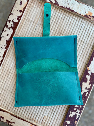 Handcrafted leather wrap wallet with visible stitching displayed on rustic wooden surface