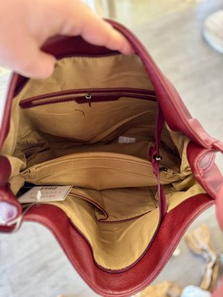 Red leather tote bag opened to show tan interior lining and multiple zippered compartments inside.