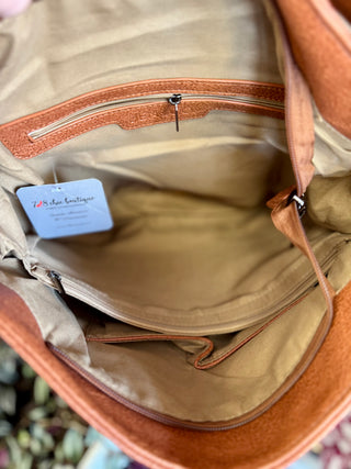Open handbag interior showing zippered pocket, fabric lining, and product tag with spacious compartments