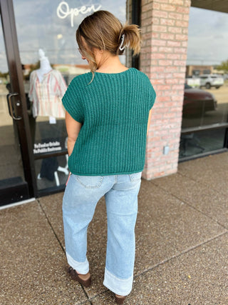 Woman wearing a ribbed knit short sleeve sweater top paired with wide-leg jeans, back view.