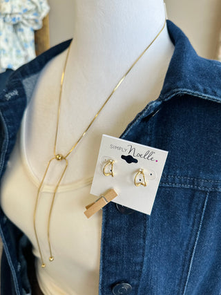 Gold Serenity adjustable lariat necklace and heart hoop earrings displayed on a mannequin.