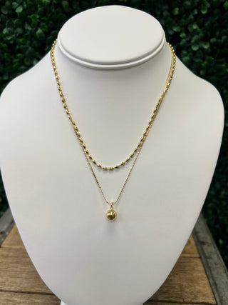 Gold layered necklace set with thick chain and thin chain with round pendant on white display bust