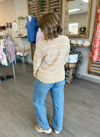 Woman wearing striped cardigan and jeans viewed from behind in clothing boutique setting
