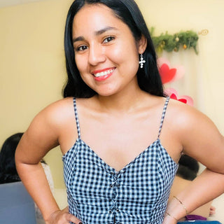 Woman smiling and wearing silver cross dangle earrings with pearl accents by Alegria Accessories.