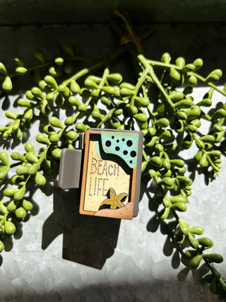 Handmade wooden hair clip with beach life design featuring wave and starfish motifs on green succulent backdrop.