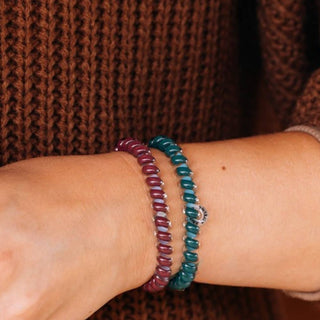 Two TELETIES small hair ties worn as bracelets on a wrist against a cozy knit sweater.