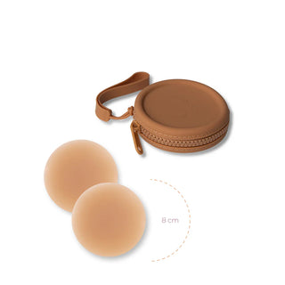 Brown silicone case with strap containing two round flesh-toned adhesive covers for discreet coverage.