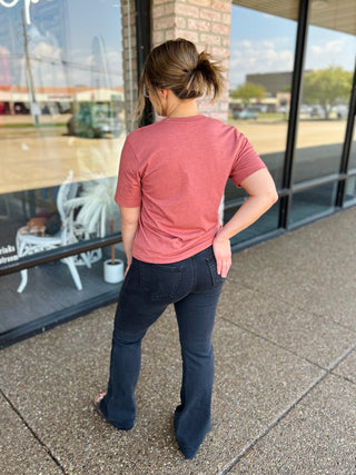 Woman wearing a casual short sleeve crew neck tee paired with dark flare jeans, back view.