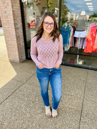 Woman wearing high rise slim straight jeans with pink sweater standing outside clothing store