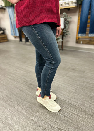 Woman wearing high rise skinny jeans with step hem and red sweater, showing fit and styling.