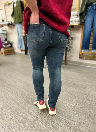 Woman wearing high-rise skinny jeans with red sweater and sneakers in clothing store