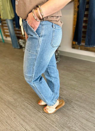 Woman wearing light blue high-waisted denim joggers with elastic waistband in casual styling pose