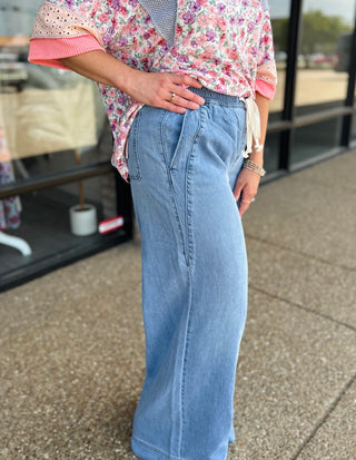 Woman wearing Hidden Jeans highrise pull-on extra wide leg jeans with drawstring waist and floral top.