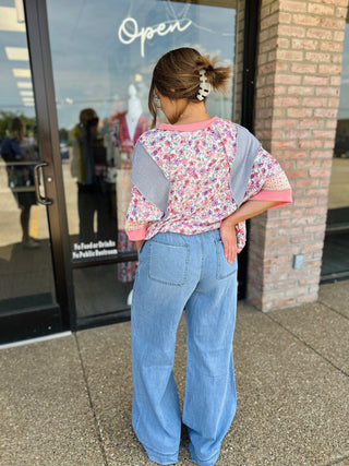 Woman wearing Hidden Jeans high-rise pull-on extra wide leg jeans, back view, outside boutique.