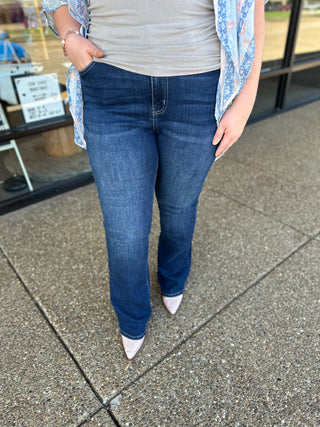 Woman wearing dark wash skinny bootcut jeans with striped top and floral cardigan, standing outdoors