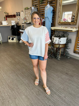 Woman wearing white striped top and blue denim shorts standing in clothing boutique store