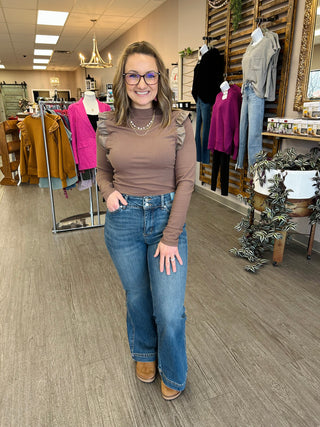 Woman modeling Judy Blue high-waisted tummy control petite flare jeans in clothing boutique store