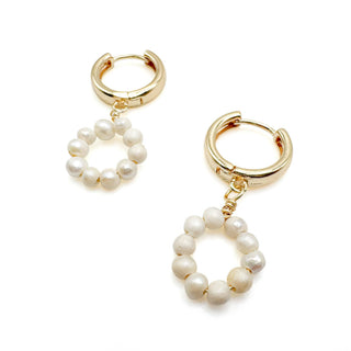 Gold hoop earrings with dangling pearl circle charms on white background