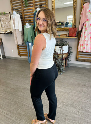 Woman wearing ivory square neck tank top and dark pants in boutique clothing store