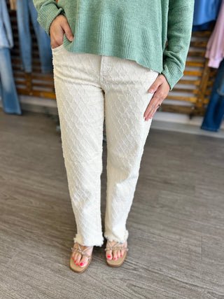 Woman wearing high-rise textured straight jeans with green sweater and sandals in retail setting