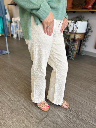 Woman wearing high-rise textured straight leg jeans with tummy control, paired with green sweater and sandals.